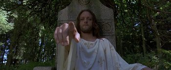 Movie still from “The Messenger: The Story of Joan of Arc” (1999), directed by Luc Besson – A man with long white hair and a beard is standing in front of a stone wall; Close Up shot, Low angle