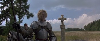 Movie still from “The Messenger: The Story of Joan of Arc” (1999), directed by Luc Besson – A man dressed as a knight standing next to a cross; Medium shot, Low angle