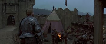 Movie still from “The Messenger: The Story of Joan of Arc” (1999), directed by Luc Besson – A group of people standing around a fire; Wide shot, High angle