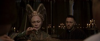 Movie still from “The Messenger: The Story of Joan of Arc” (1999), directed by Luc Besson – A woman in a headpiece is holding a glass; Close Up shot, Over the shoulder angle