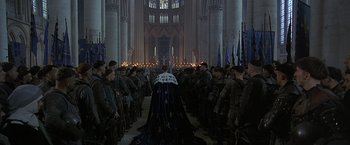 Movie still from “The Messenger: The Story of Joan of Arc” (1999), directed by Luc Besson – A group of people in a church with candles in front of them; Extreme Wide shot, High angle