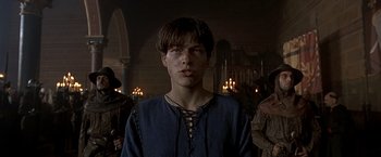 Movie still from “The Messenger: The Story of Joan of Arc” (1999), directed by Luc Besson – A young man in medieval garb standing in front of a group of people; Close Up shot, Low angle