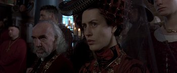 Movie still from “The Messenger: The Story of Joan of Arc” (1999), directed by Luc Besson – A woman in a red dress with a black hat on her head; Close Up shot, Over the shoulder angle