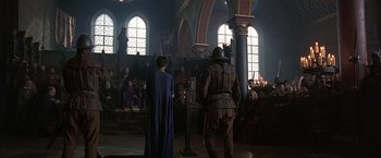 Movie still from “The Messenger: The Story of Joan of Arc” (1999), directed by Luc Besson – Two people in medieval garb stand in front of a group of people; Wide shot, High angle