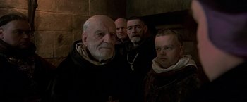 Movie still from “The Messenger: The Story of Joan of Arc” (1999), directed by Luc Besson – A group of men standing next to each other in a room; Medium shot, Low angle