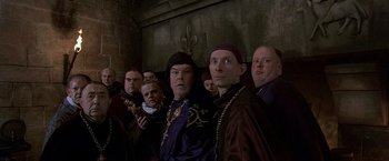 Movie still from “The Messenger: The Story of Joan of Arc” (1999), directed by Luc Besson – A group of men standing next to each other in front of a wall; Medium shot, Low angle