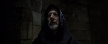 Movie still from “The Messenger: The Story of Joan of Arc” (1999), directed by Luc Besson – A man with a beard wearing a black robe; Close Up shot, Low angle