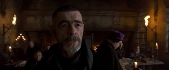 Movie still from “The Messenger: The Story of Joan of Arc” (1999), directed by Luc Besson – An older man with a beard and a mustache; Close Up shot, Over the shoulder angle