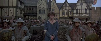 Movie still from “The Messenger: The Story of Joan of Arc” (1999), directed by Luc Besson – A woman in chains standing in front of a group of soldiers; Medium shot, Low angle