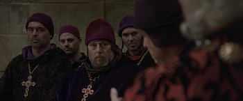 Movie still from “The Messenger: The Story of Joan of Arc” (1999), directed by Luc Besson – A group of men in medieval garb looking at each other; Close Up shot, Over the shoulder angle