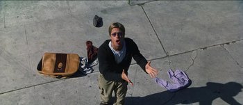 Movie still from “The Mexican” (2001), directed by Gore Verbinski – A man standing on a sidewalk with his hands outstretched; Medium shot, Overhead angle