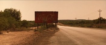 Movie still from “The Mexican” (2001), directed by Gore Verbinski – An old coca - cola sign on the side of the road; Extreme Wide shot, Low angle