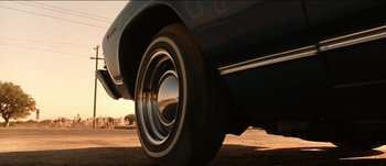 Movie still from “The Mexican” (2001), directed by Gore Verbinski – View of a car's tire and wheel on the road; Wide shot, Low angle