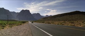 Movie still from “The Mexican” (2001), directed by Gore Verbinski – A car driving down a road in the middle of the desert; Extreme Wide shot, Low angle