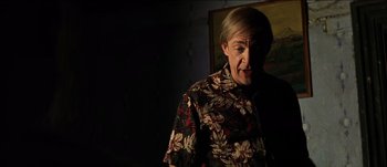 Movie still from “The Mexican” (2001), directed by Gore Verbinski – An older woman in a floral shirt is looking at the camera; Medium shot, Over the shoulder angle