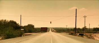 Movie still from “The Mexican” (2001), directed by Gore Verbinski – An empty road with a red traffic light hanging above it; Extreme Wide shot, Low angle