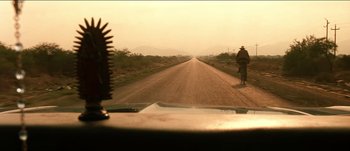 Movie still from “The Mexican” (2001), directed by Gore Verbinski – A man riding a bike down a dirt road; Extreme Wide shot, Low angle