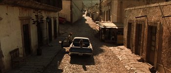 Movie still from “The Mexican” (2001), directed by Gore Verbinski – Two people are sitting in the back of an old car; Extreme Wide shot, High angle