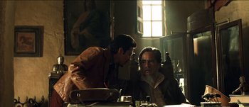 Movie still from “The Mexican” (2001), directed by Gore Verbinski – Two men are sitting at a table in a room; Medium shot, Over the shoulder angle