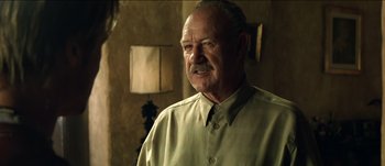 Movie still from “The Mexican” (2001), directed by Gore Verbinski – An older man wearing a green shirt in front of a lamp; Close Up shot, Low angle