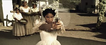 Movie still from “The Mexican” (2001), directed by Gore Verbinski – A woman in a white dress is holding a gun; Medium shot, Low angle