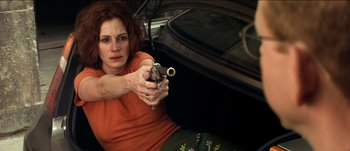 Movie still from “The Mexican” (2001), directed by Gore Verbinski – A woman holding a gun in her hand while sitting in a car; Medium shot, Low angle