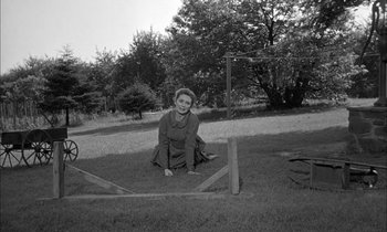 Movie still from “The Miracle Worker” (1962), directed by Arthur Penn – An old black and white photo of a woman kneeling in the grass; Wide shot, High angle