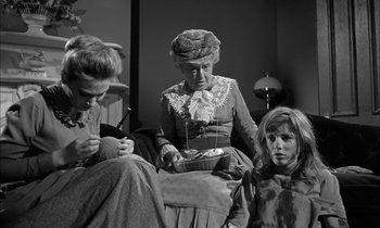 Movie still from “The Miracle Worker” (1962), directed by Arthur Penn – A woman and two children sitting on a chair; Medium shot, Low angle