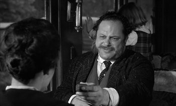 Movie still from “The Miracle Worker” (1962), directed by Arthur Penn – A black and white photo of a man on a train looking at his cell phone; Medium shot, Over the shoulder angle