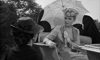Movie still from “The Miracle Worker” (1962), directed by Arthur Penn – Two women sitting under an umbrella talking to each other; Medium shot, Over the shoulder angle