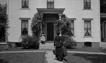 Movie still from “The Miracle Worker” (1962), directed by Arthur Penn – An old woman carrying luggage walks down the sidewalk; Wide shot, Low angle