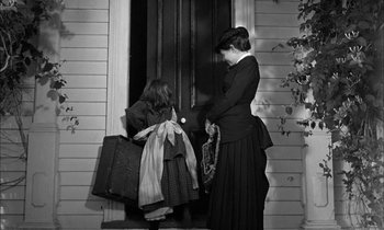 Movie still from “The Miracle Worker” (1962), directed by Arthur Penn – A woman and a girl holding suitcases in front of a door; Medium shot, Over the shoulder angle