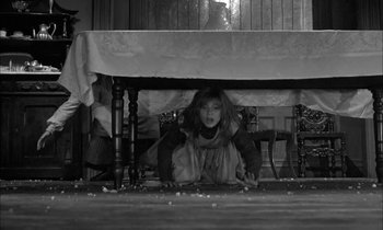 Movie still from “The Miracle Worker” (1962), directed by Arthur Penn – A little girl hiding under a dining room table; Wide shot, High angle