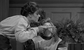 Movie still from “The Miracle Worker” (1962), directed by Arthur Penn – A woman cutting another woman's hair with a plate; Medium shot, Over the shoulder angle