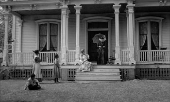 Movie still from “The Miracle Worker” (1962), directed by Arthur Penn – An old photo of a woman sitting on the steps of a house; Extreme Wide shot, Low angle