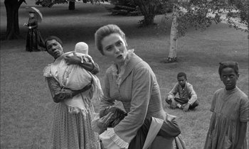 Movie still from “The Miracle Worker” (1962), directed by Arthur Penn – A black - and - white photo of a woman holding a baby; Medium shot, Over the shoulder angle