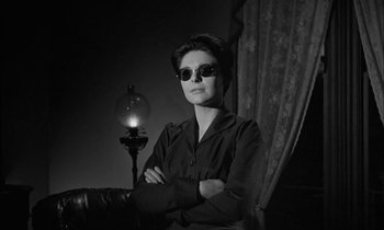 Movie still from “The Miracle Worker” (1962), directed by Arthur Penn – A woman wearing sunglasses standing in front of a lamp; Medium shot, Low angle