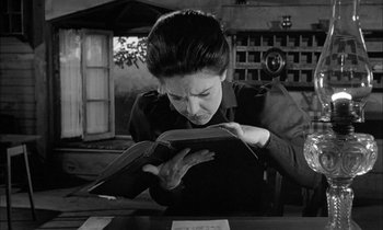 Movie still from “The Miracle Worker” (1962), directed by Arthur Penn – A woman is reading a book in a black and white photo; Close Up shot, Low angle