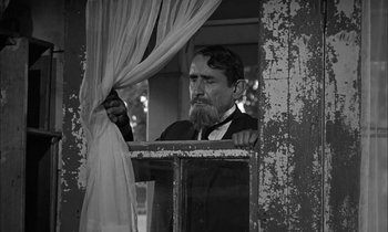 Movie still from “The Miracle Worker” (1962), directed by Arthur Penn – A man with a long beard looking out of a window; Medium shot, Low angle