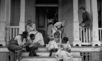 Movie still from “The Miracle Worker” (1962), directed by Arthur Penn – An old photo of people sitting on the steps of a house; Wide shot, High angle