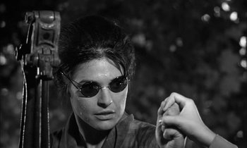 Movie still from “The Miracle Worker” (1962), directed by Arthur Penn – A woman wearing sunglasses and holding something in her hand; Close Up shot, Over the shoulder angle