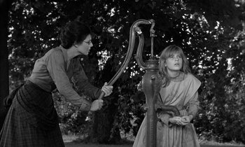 Movie still from “The Miracle Worker” (1962), directed by Arthur Penn – Two women are standing next to an old fashioned water pump; Medium shot, Low angle