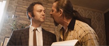 Movie still from “The Misfortunates” (2009), directed by Felix van Groeningen – Two men in business suits talking to each other; Medium shot, Over the shoulder angle