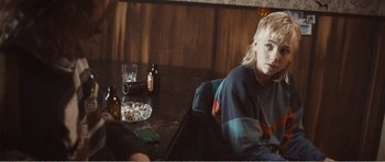 Movie still from “The Misfortunates” (2009), directed by Felix van Groeningen – A person sitting at a table with a glass of beer; Medium shot, Over the shoulder angle