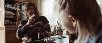 Movie still from “The Misfortunates” (2009), directed by Felix van Groeningen – A man sitting at a table in front of a bottle of beer; Medium shot, Over the shoulder angle