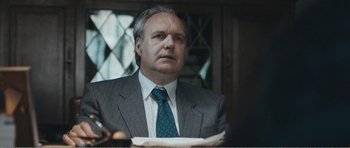 Movie still from “The Misfortunates” (2009), directed by Felix van Groeningen – A man wearing a suit and tie sitting at a table; Close Up shot, Low angle