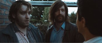 Movie still from “The Misfortunates” (2009), directed by Felix van Groeningen – A man with long hair standing next to another man with long hair; Medium shot, Low angle