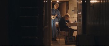 Movie still from “The Misfortunates” (2009), directed by Felix van Groeningen – Two people sitting at a dining room table writing; Medium shot, Over the shoulder angle