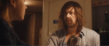 Movie still from “The Misfortunates” (2009), directed by Felix van Groeningen – A man with long brown hair is looking at a camera; Close Up shot, Over the shoulder angle