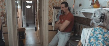 Movie still from “The Misfortunates” (2009), directed by Felix van Groeningen – A man standing in front of a wall with his arms crossed; Medium shot, Over the shoulder angle